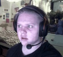 a man wearing headphones and a microphone looks at the camera with a surprised look on his face