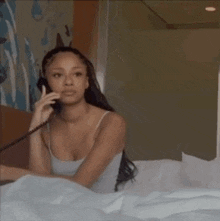 a woman is laying in bed talking on a phone