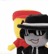a stuffed animal wearing a hat and sunglasses is standing next to a stuffed animal wearing a red hat .