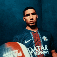 a man in a qatar airways jersey holds a ball