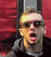 a man wearing sunglasses is making a funny face with his mouth open