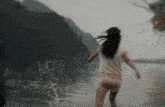 a woman in a white shirt and shorts is running through a body of water