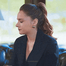 a woman in a suit and earrings is sitting on a couch .