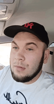 a man with a beard wearing a ny hat and a white shirt