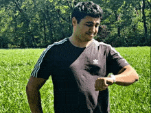 a man wearing an adidas t-shirt is looking at his watch