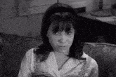 a black and white photo of a young girl sitting on a couch .