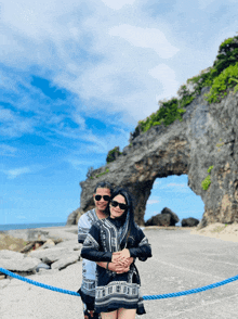 a man and a woman are posing for a photo in front of a rock formation