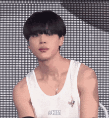 a close up of a man wearing a white tank top and a necklace .
