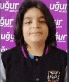a young boy is standing in front of a purple wall .