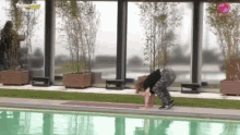 a woman is doing a yoga pose in front of a swimming pool and a sign that says big brother