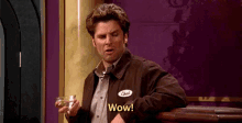 a man in a brown jacket is holding a drink and says wow .