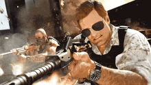 a man wearing sunglasses and a watch is holding a rifle