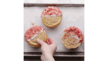 a person is picking up a cookie from a tray with three cookies on it .