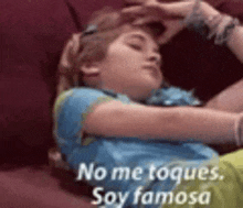 a girl is laying on a couch with her hand on her forehead and the words `` no me toques , soy famosa ''