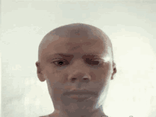 a man with a shaved head is looking at the camera with a serious look on his face .