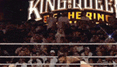 a crowd of people watching a wrestling match in front of a sign that says king roger the ring