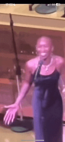 a woman in a blue dress is singing into a microphone on stage .