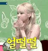 a woman covering her mouth with her hands in front of a green wall with chinese writing