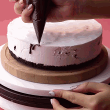 a person is icing a cake with a bag of chocolate
