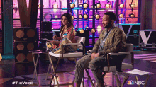 a man and a woman are sitting in chairs in a room with a nbc logo in the corner