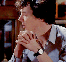 a man wearing a watch on his wrist looks to his left