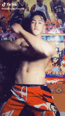 a shirtless man is dancing in front of a pinball machine with basketball players in the background .