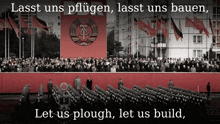 a large crowd of people are gathered in front of a red banner that says lasst uns pflugen lasst uns bauen