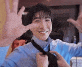 a man is putting on a tie and smiling while making a funny face .