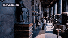 a very long hallway with a lot of statues on the wall and columns .