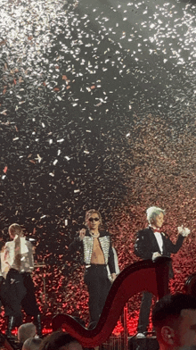 a group of people on stage with confetti falling from the sky