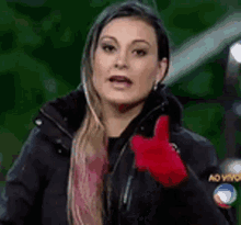 a woman in a black jacket is giving a thumbs up sign .