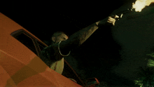 a man is holding a gun with flames coming out of it while sitting in a car