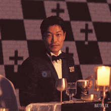 a man in a tuxedo sits at a table with netflix written on the bottom