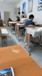 a classroom with people sitting at their desks and a phone on the desk