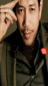a man wearing a green jacket has a red letter s on his chest
