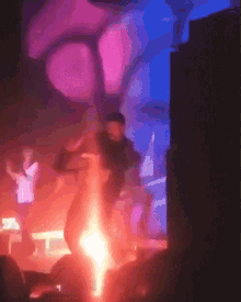 a group of people are dancing in a dark room with a purple light behind them