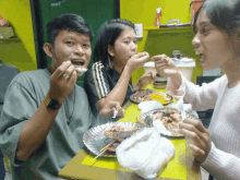 a group of people are sitting at a table eating food and one of them is wearing a watch