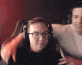 a man wearing glasses and headphones is sitting next to another man in a chair