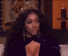 a woman wearing a tiara and a purple dress is sitting on a couch