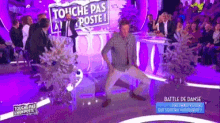 a man is dancing on a stage with a sign that says touche pas poste on it