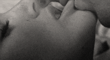 a black and white photo of a man and a woman kissing .
