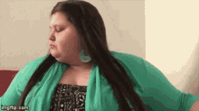 a very fat woman with long hair is wearing a green sweater .