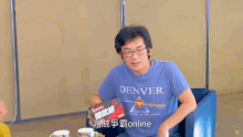 a man wearing a denver shirt sits at a table with another man