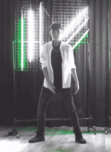 a man in a white shirt and black pants is dancing in a room with neon lights .