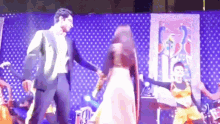 a man and a woman are dancing on a stage with a drummer in the background .