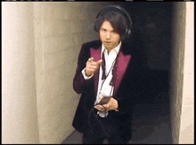 a man in a purple suit and headphones is pointing