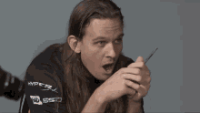 a man with long hair is wearing a black shirt with the word hyper on it