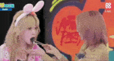 a girl with bunny ears is eating food with chopsticks while another girl watches .