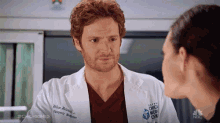 a man in a white lab coat is talking to a woman in a hospital .