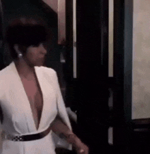 a woman in a white dress with a plunging neckline is standing in a room .